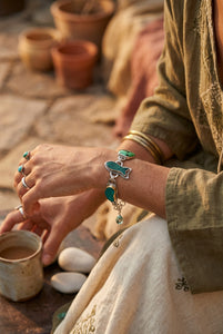 A silver chain bracelet featuring five irregular-shaped green and blue marbled gemstones, displayed on a white background with a checkerboard transparency pattern.