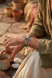 A silver bracelet with irregular green and turquoise stone accents,  displayed on model