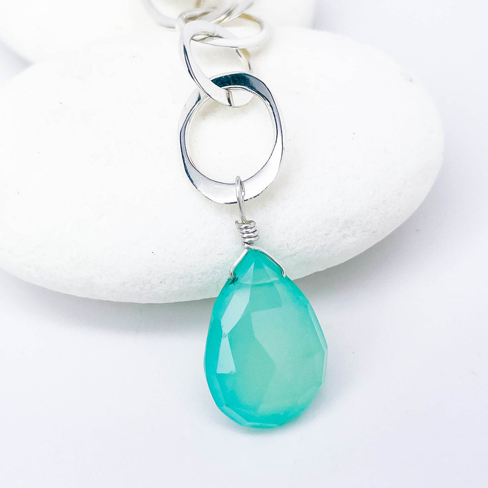Faceted chalcedony teardrop pendant on a silver chain against a white background