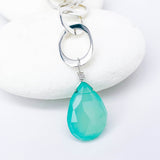 Faceted chalcedony teardrop pendant on a silver chain against a white background