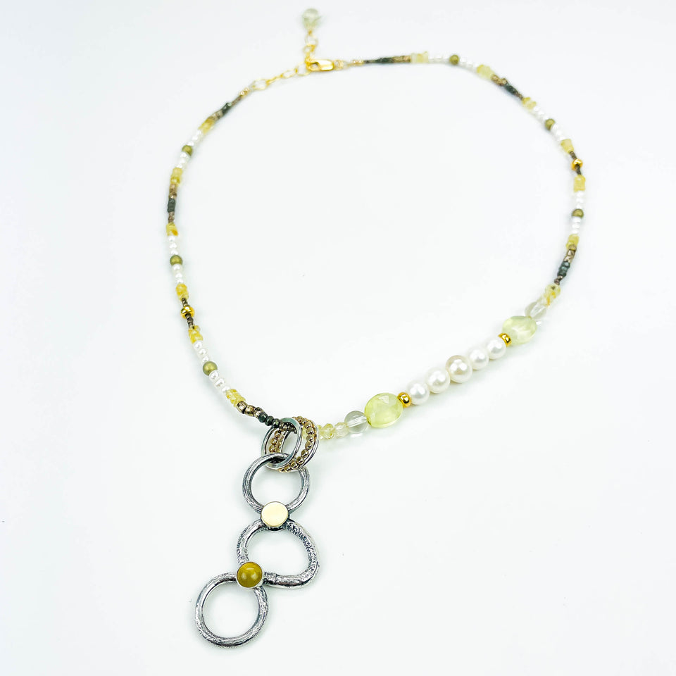 Necklace with circular pendant and beaded chain on a white background