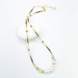 Beaded necklace with green, gold, and clear beads on a white background