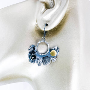 Pair of silver earrings with black spinel and gold accents on manequin