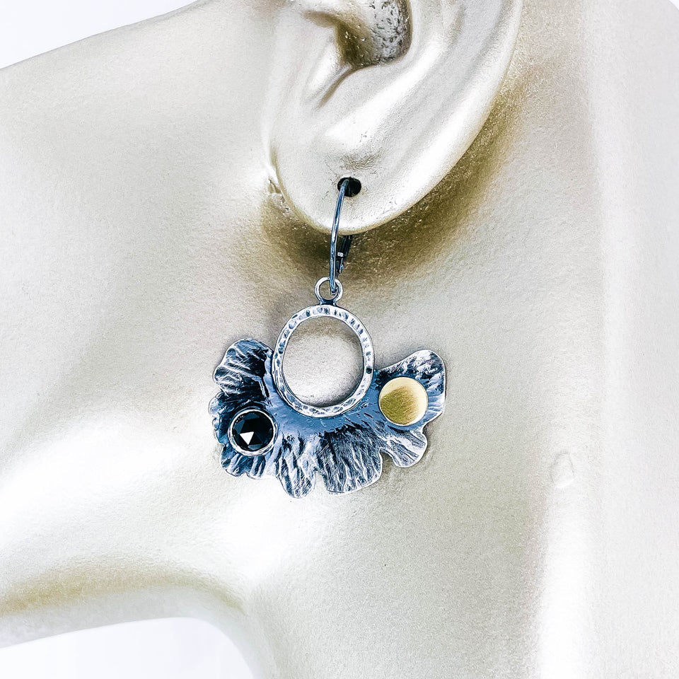 Pair of silver earrings with black spinel and gold accents on manequin