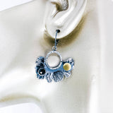 Pair of silver earrings with black spinel and gold accents on manequin