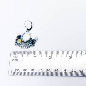 Pair of silver earrings with black spinel and gold accents on handcrafted leaf with ruler depicting measurement.  