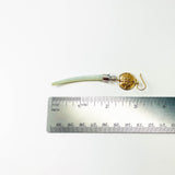 Bronze earring with a green dentilium next to a ruler on a white background