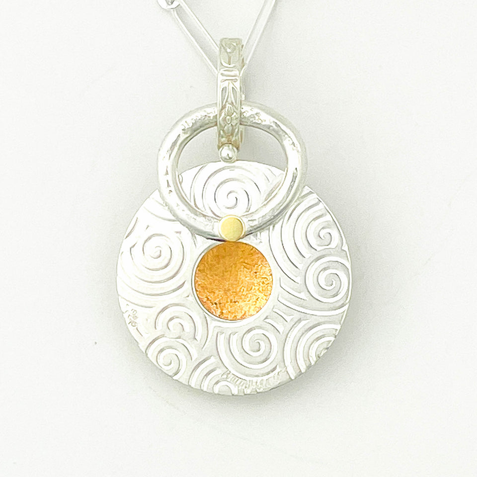 Silver pendant with gold center on a white background