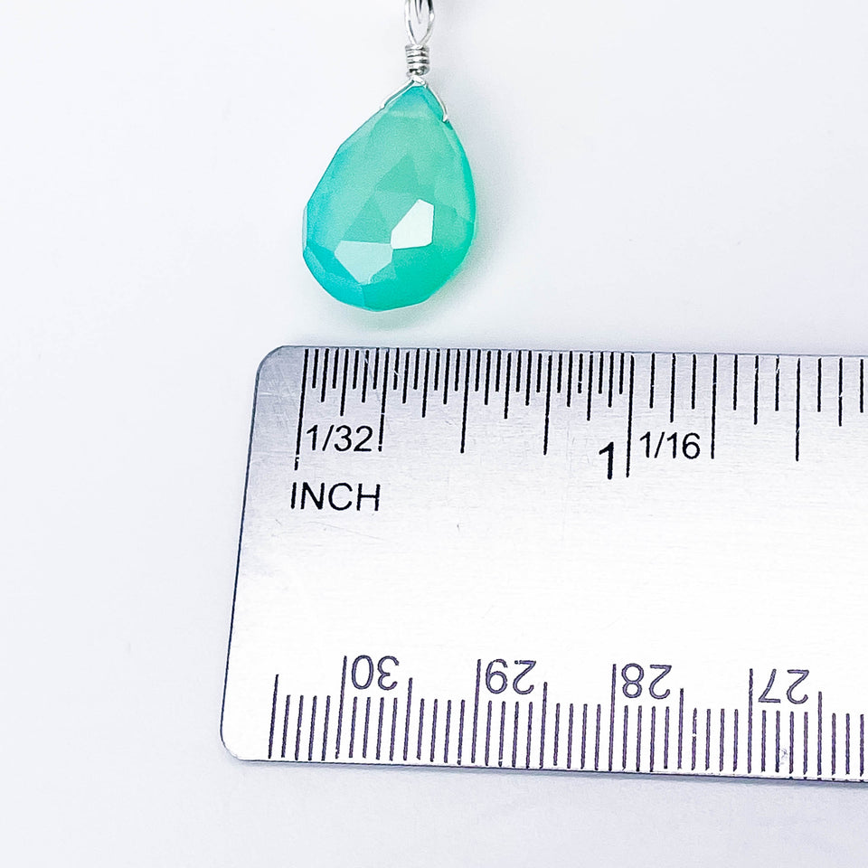 Teal teardrop pendant with silver wire on a ruler for scale