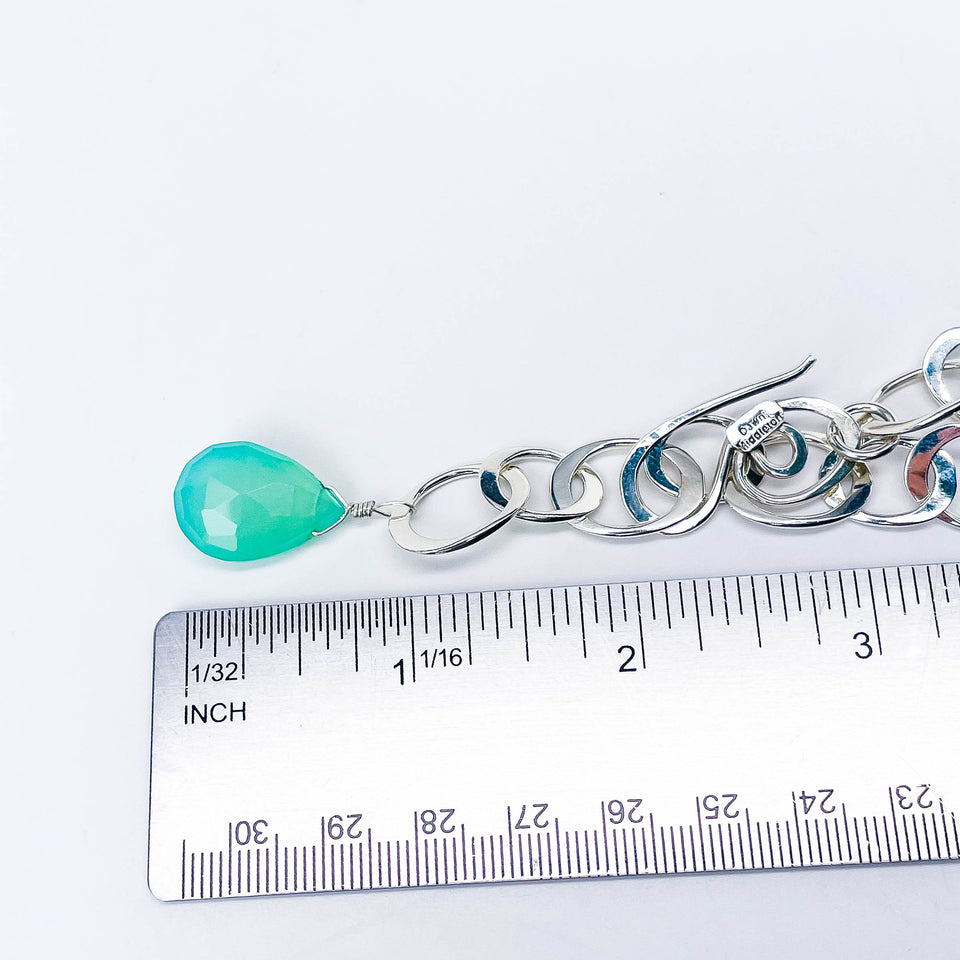 chunky silver chain with  a teardrop-shaped chalcedony charm next to a ruler for size reference.